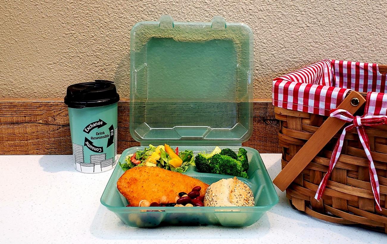 Reusable green to-go drink cup and food container with food inside