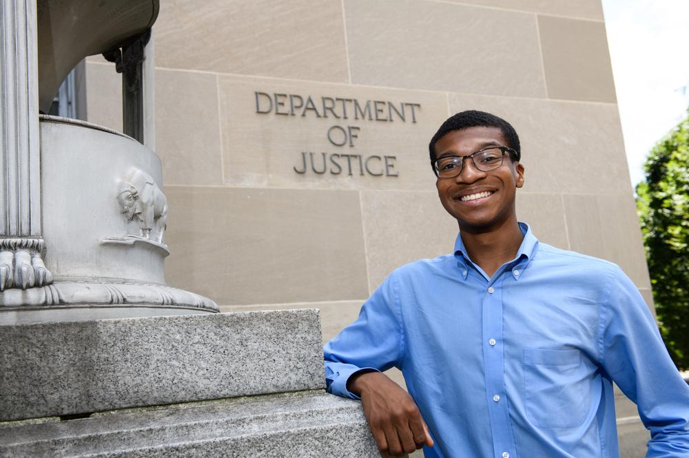 Noah Massillon in front of the Department of Justice building