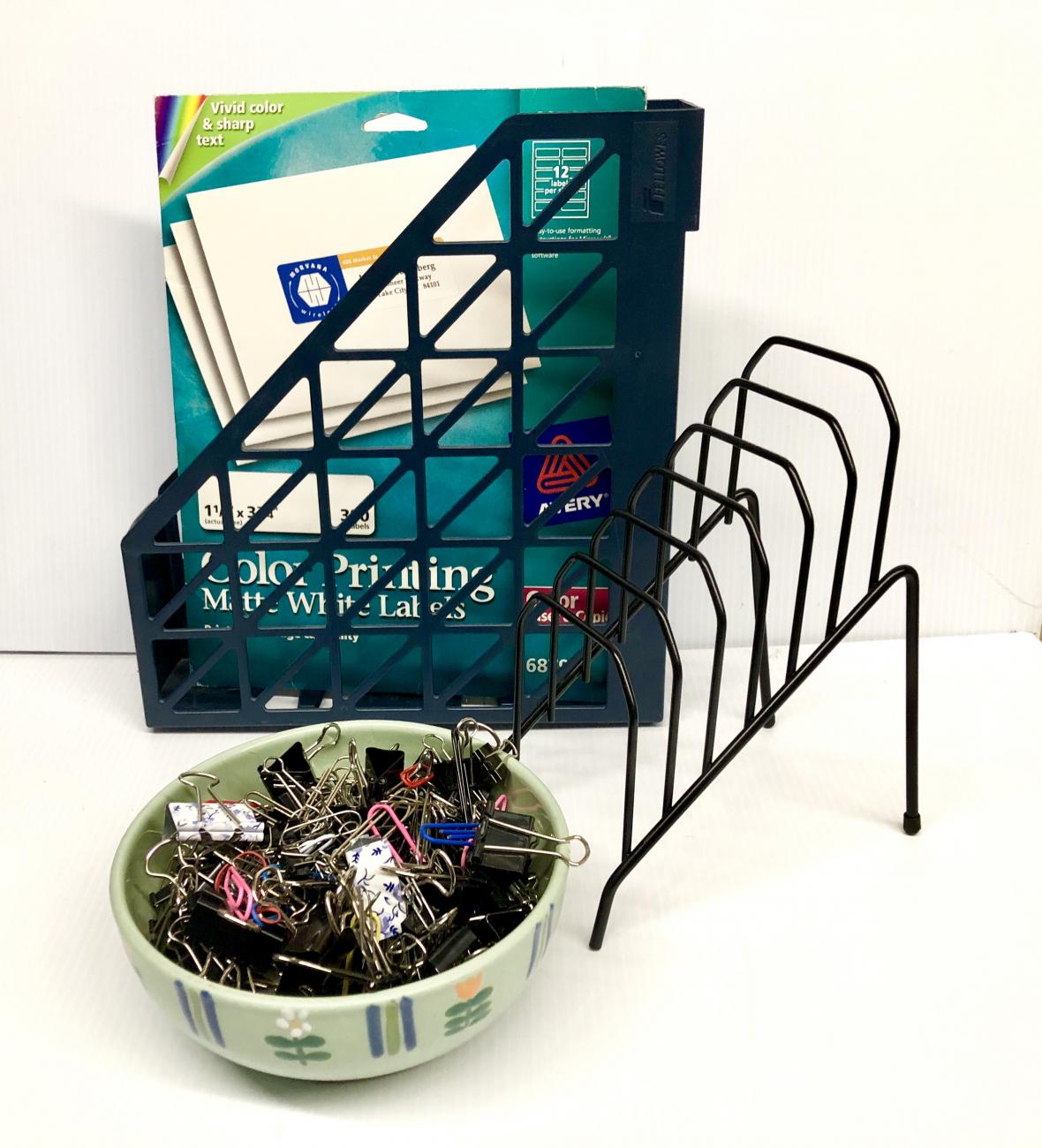 A bowl of binder clips sits in front of two desk organizers: one containing color printing paper